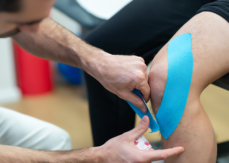 Applicazione di kinesio taping sul ginocchio durante un trattamento di fisioterapia presso Rinnova Medical a Nova Milanese.