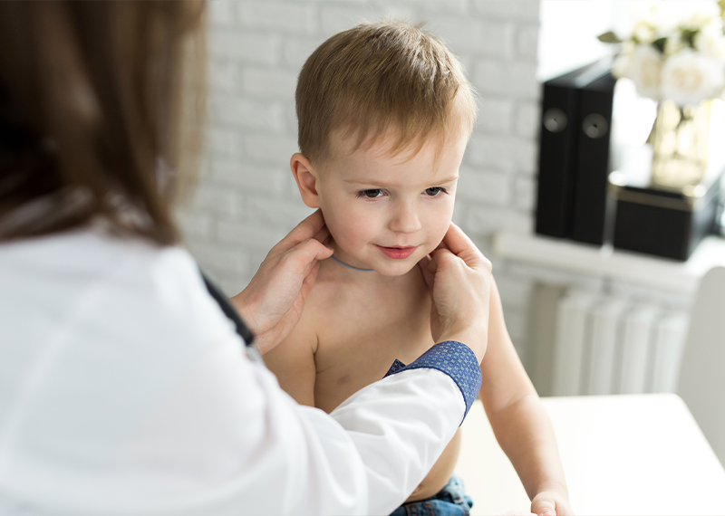 Pediatra durante la visita di controllo di un bambino con valutazione del collo e dei linfonodi.